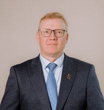 Vīrietis uzvalkā uz gaiša fona