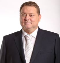 Vīrieša profils tumšās drēbēs uz gaiša fona