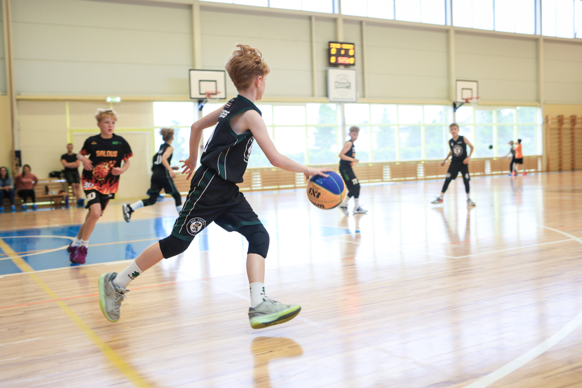 Puiši spēlē basketbola sporta zālē