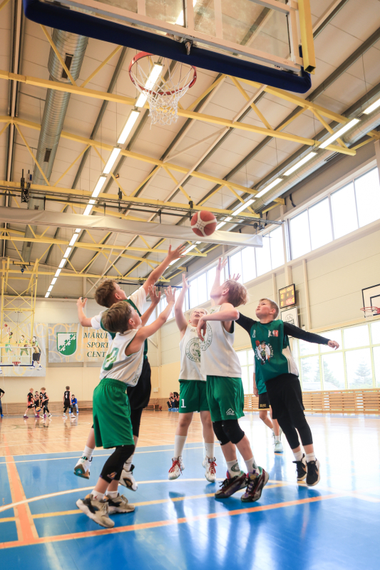 Puiši spēlē basketbola sporta zālē