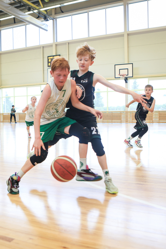 Puiši spēlē basketbola sporta zālē