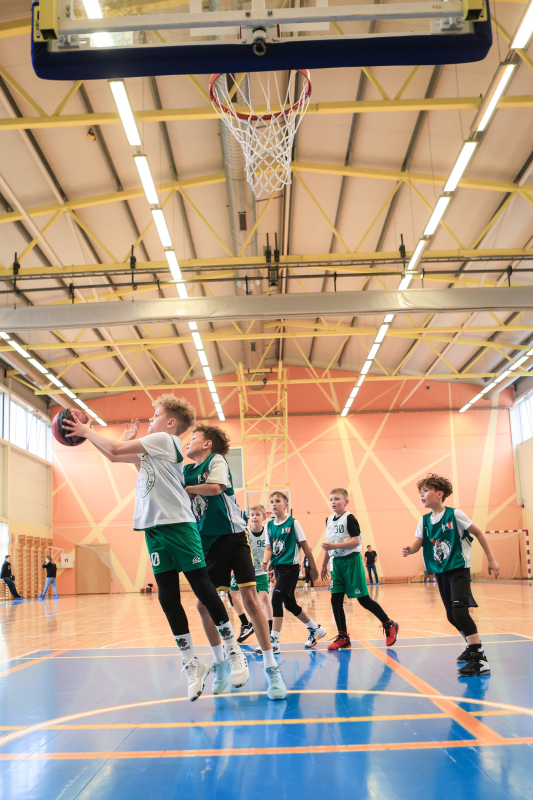 Puiši spēlē basketbola sporta zālē