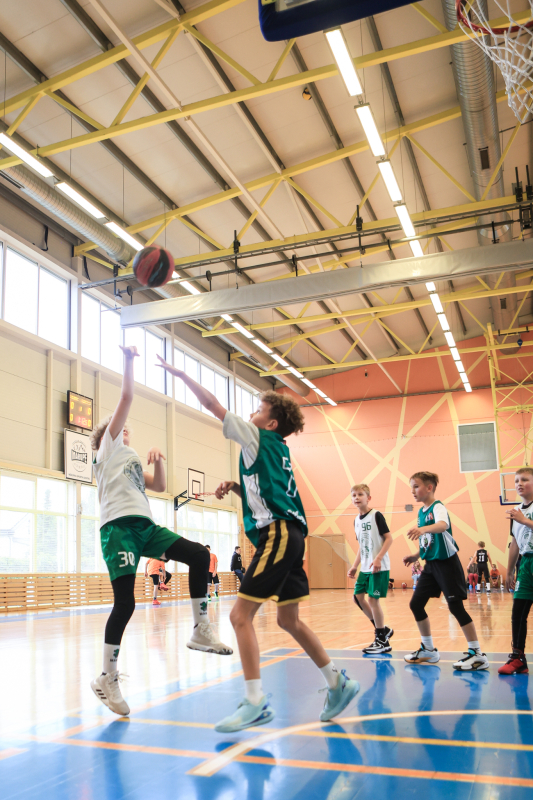Puiši spēlē basketbola sporta zālē
