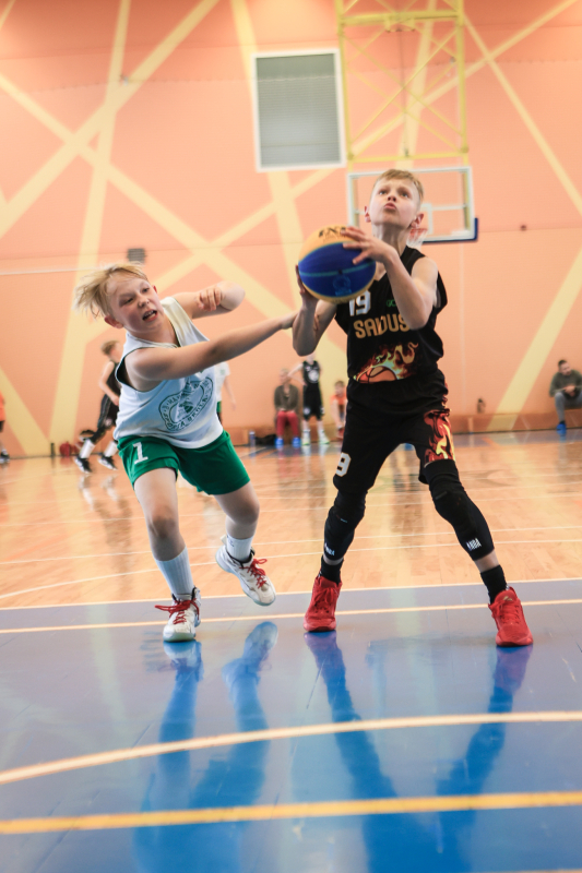Puiši spēlē basketbola sporta zālē