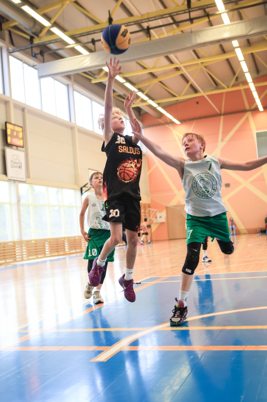 Puiši spēlē basketbola sporta zālē