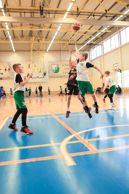 Puiši spēlē basketbola sporta zālē