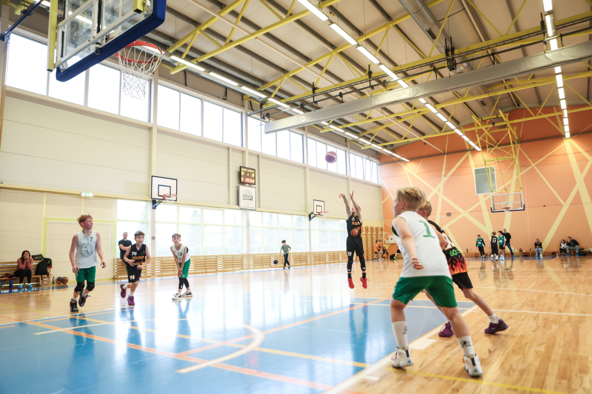 Puiši spēlē basketbola sporta zālē