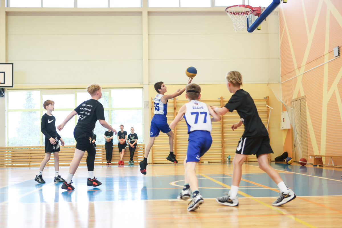 Puiši spēlē basketbola sporta zālē