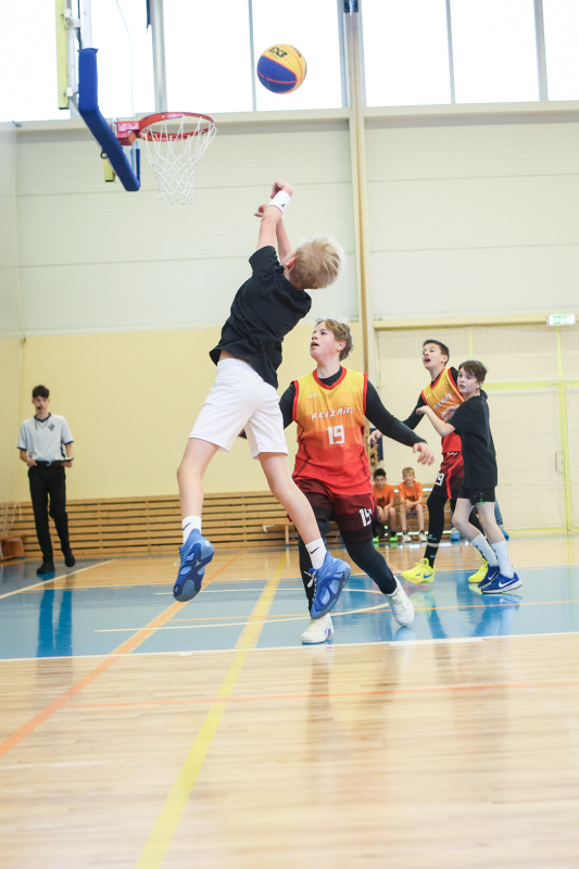 Puiši spēlē basketbola sporta zālē