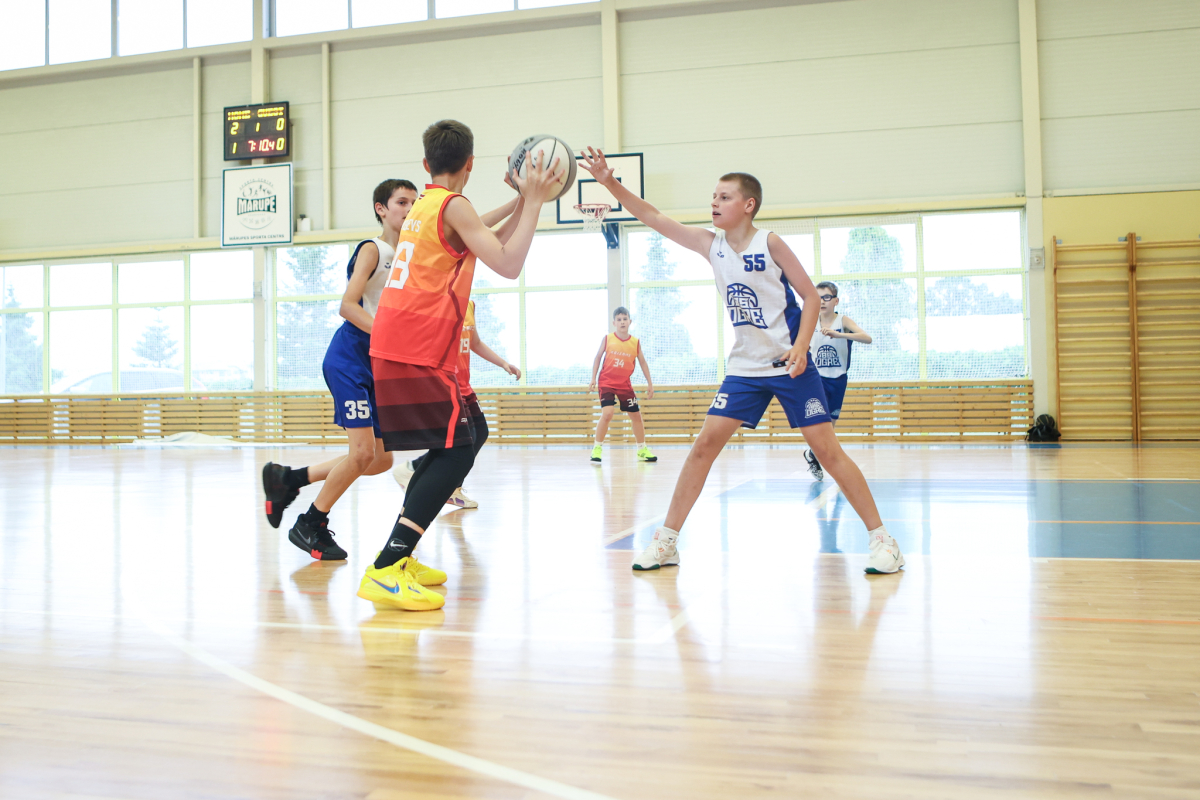 Puiši spēlē basketbola sporta zālē