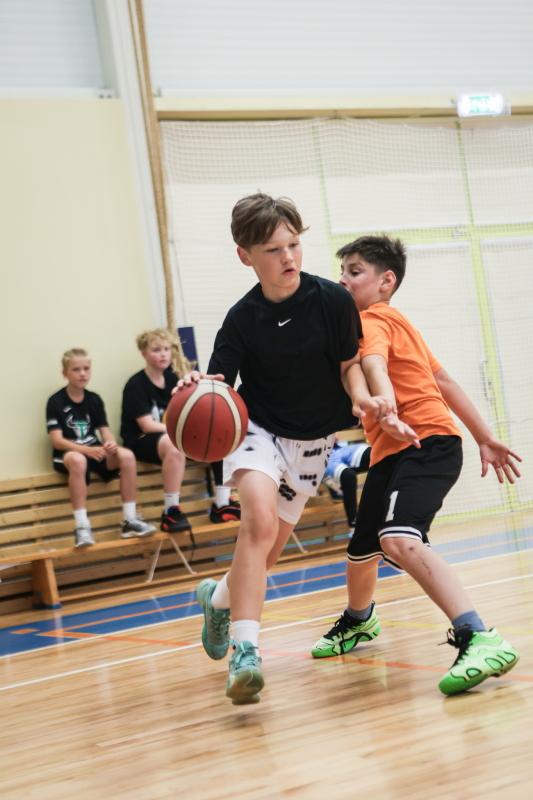 Puiši spēlē basketbola sporta zālē