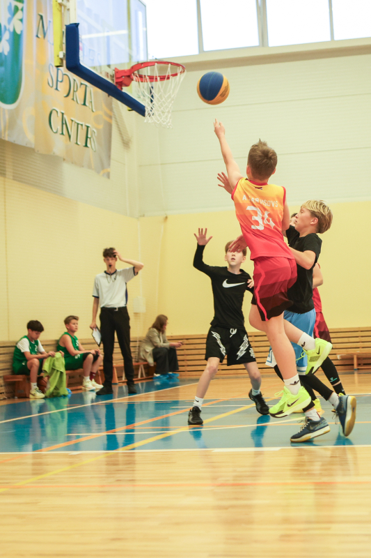 Puiši spēlē basketbola sporta zālē