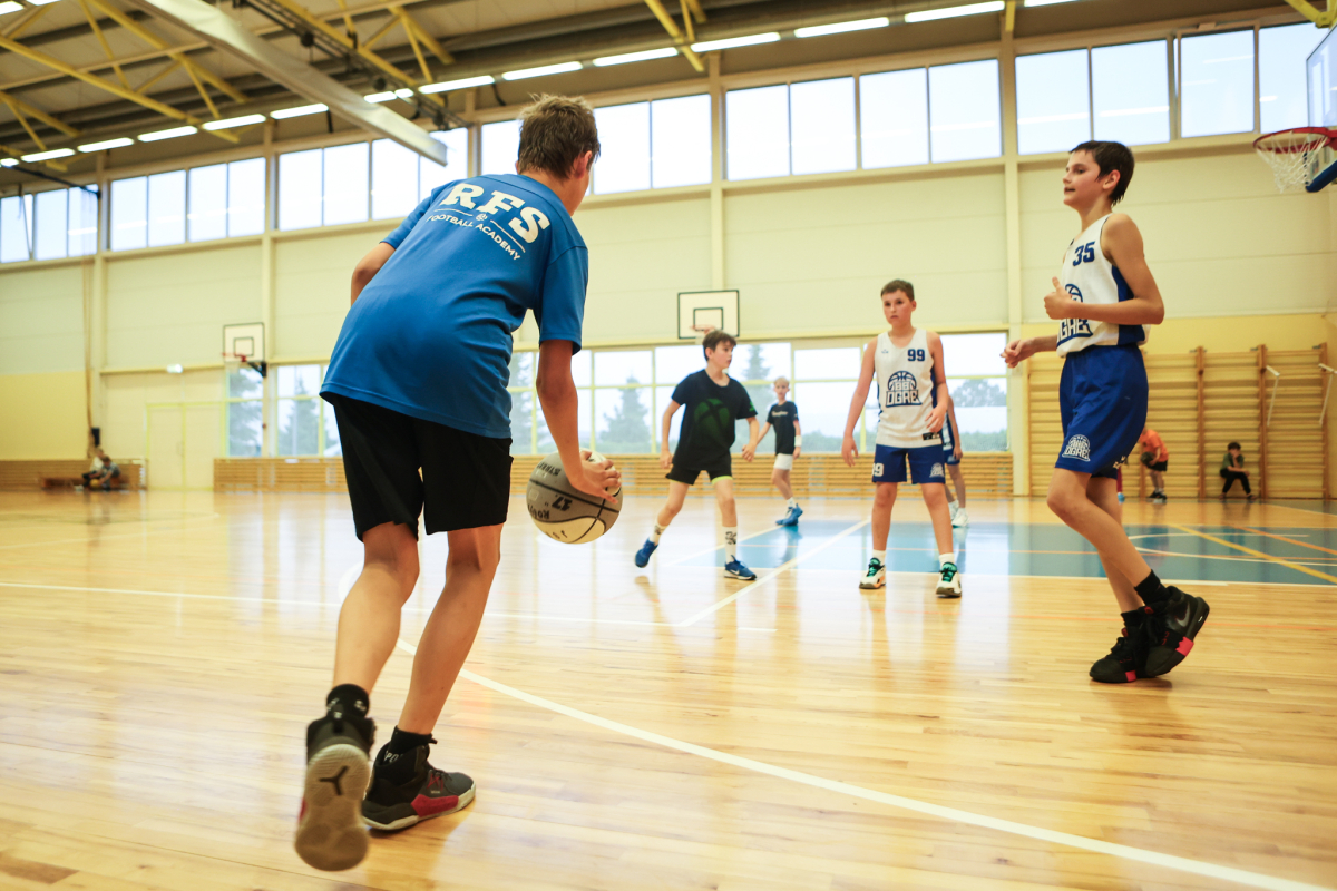 Puiši spēlē basketbola sporta zālē