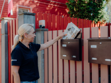 Sieviete met pastkastītē avīzi