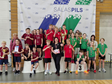 Daudz skolēni sporta tērpos stāv uz pjedestāla