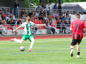 Puisi zaļganbaltā sporta tērpā sit pa futbola bumbu