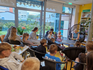 Bērni bibliotēkas telpās ar grāmatām rokās