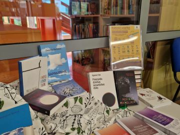 Grāmatas un bukleti izstādē uz galda gaišā telpā