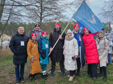 Vairāki cilvēki stāv ar karogu rokās