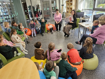 Daudz bērni apsēdušies aplī uz grīdas