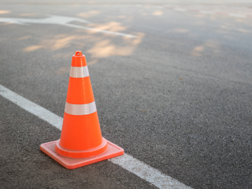 Asfaltēts ceļš un krāsains konuss informācijai par būvdarbiem