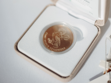 Monēta gaišā kastītē uz gaiša fona