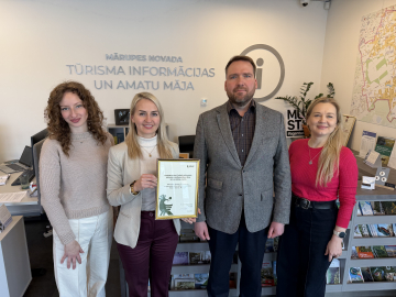 Trīs sievietes un vīrietis kopbildē gaišā telpā