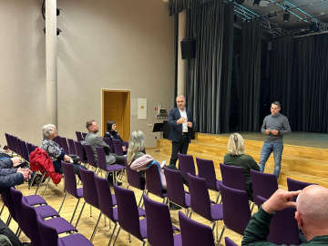 Cilvēku grupa zālē sanāksmē