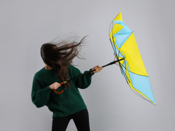 Gaiši pelēks fons ar krāsaina lietussarga un personas siluetu