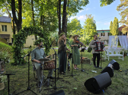 Četru cilvēku mūzikas grupa ar instrumentiem pie mikrofoniem brīvdabas koncertā