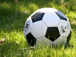 Melnbalta futbola bumba zaļā zālienā