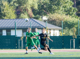 Trīs futbolisti zālienā cīnās par bumbu virs galvas
