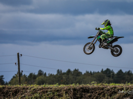 Motokrosa braucējs palēcies gaisā virs dubļu trases
