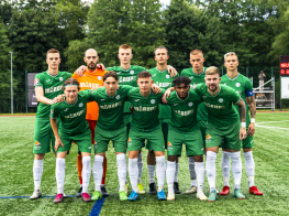 Puiši zaļos sporta kostīmos stāv futbola laukumā