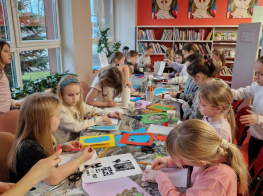 Bērnu pulks radošajā nodarbībā sēž pie galda un veido kartiņas