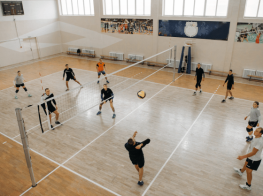 volejbola zāle ar spēlētājiem pie volejbola tīkla