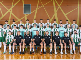Vīriešu komanda baltos kreklos oranžā sporta zālē