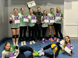 Vīrietis ar konfekšu kasti rokās un apkārt meitenes zaļās sporta jakās