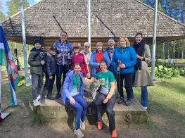 Cilvēki sporta tērpos sēž brīvdabā