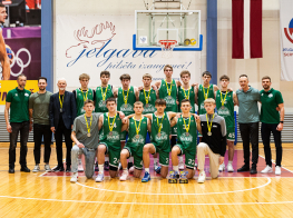 Basketbolisti zaļos sporta tērpos stāv pie balta plakāta sporta zālē