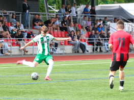Puisi zaļganbaltā sporta tērpā sit pa futbola bumbu