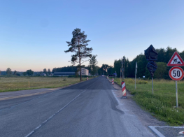 Asfaltēta iela starp laukiem un mežu