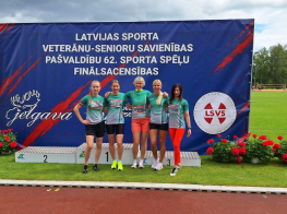 Vairākas sievietes zaļos sporta kreklos pie balta pjedestāla
