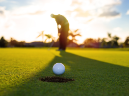 Vīrietis saulrietā, kurš spēlē golfu (siluets)