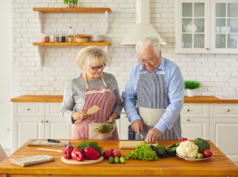 Divi seniori gatavo ēdienu pie koka galda