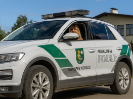 Fotogrāfija ar Mārupes novada pašvaldības policijas automašīnu un pie stūres pašvaldības policijas darbiniece
