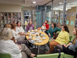 Grāmatu klubiņa dalībnieki sēž ap galdu