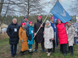 Vairāki cilvēki stāv ar karogu rokās
