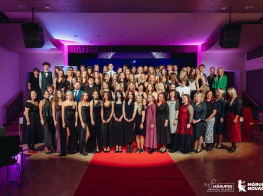 Jauniešu pasākuma laureātu kopbilde uz krāsainu skatuves gaismu fona