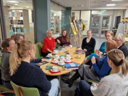 Cilvēku pulks ar grāmatu galdu tikšanās laikā